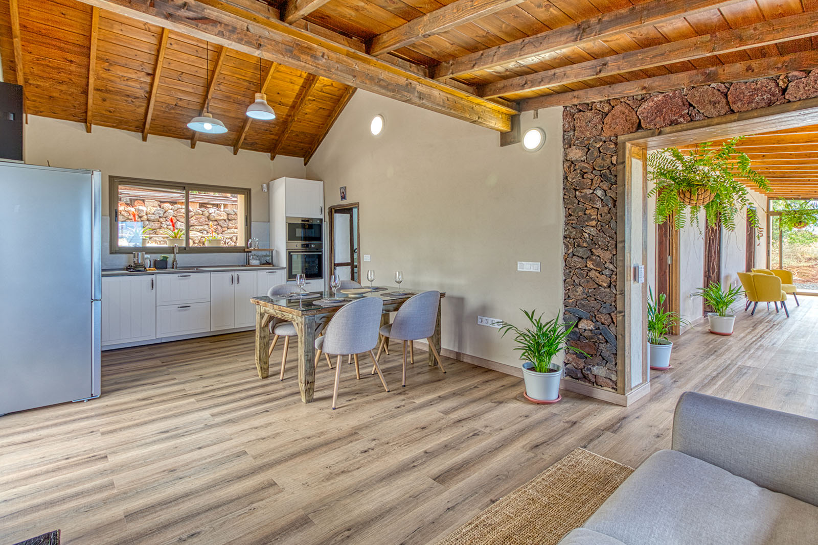Open woon-, eet- en keukenruimte van Casa Nazaret met natuurstenen muren en Canarisch houten plafond