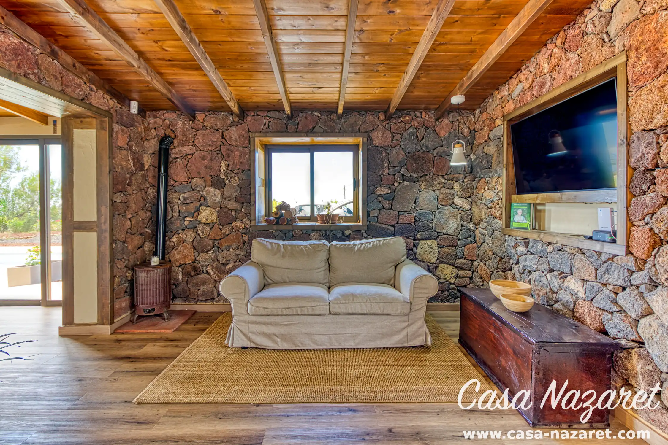 Comfortabele woonkamer bij Casa Nazaret in Puntagorda met traditionele natuurstenen muren en houten balkenplafond